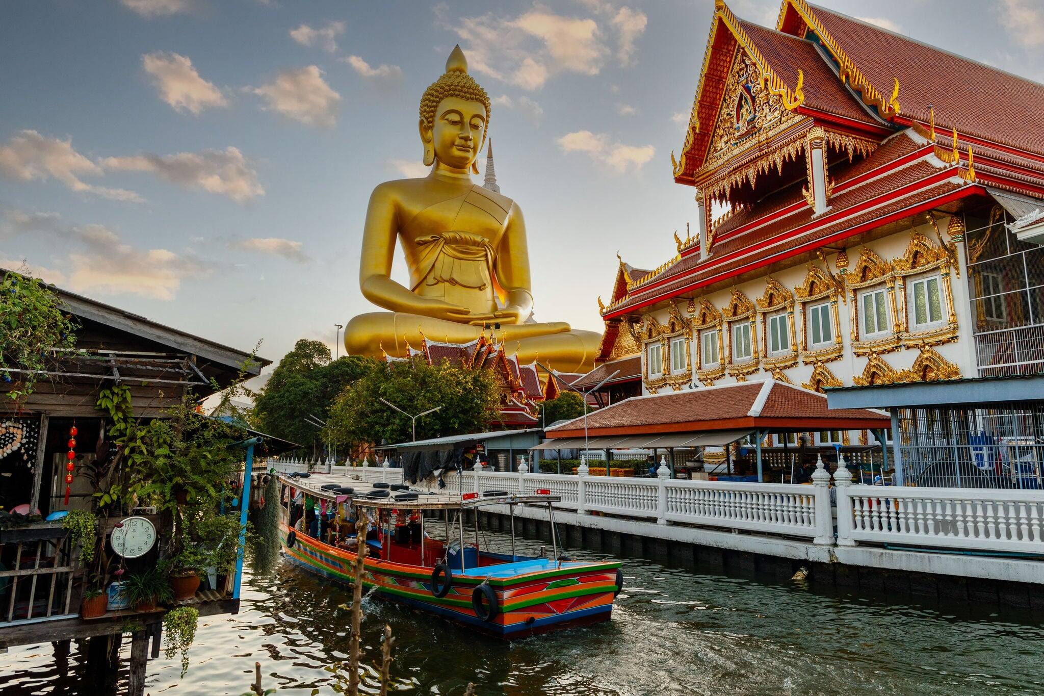 Big Buddha Dhammakaya Tep Mongkol Buddha of Paknam Bhasicharoen temple in Thonburi in Bangkok city against the backdrop of sunset and canal