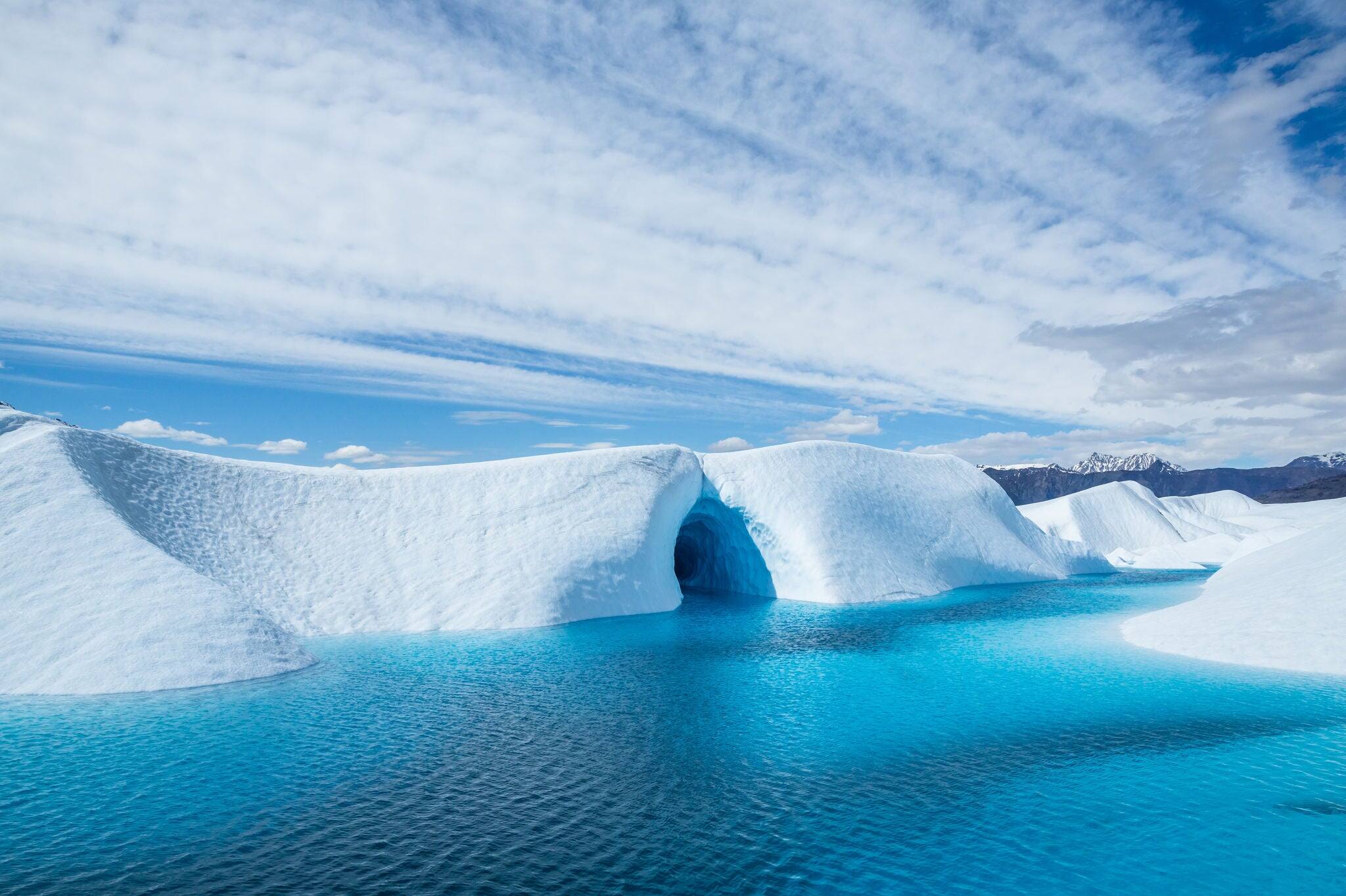 Crystal blue water flooded an ice cave on the surface of the Matanuska Glacier in Alaska. The pool has formed from melting ice of the glacier in warm sunny weather.