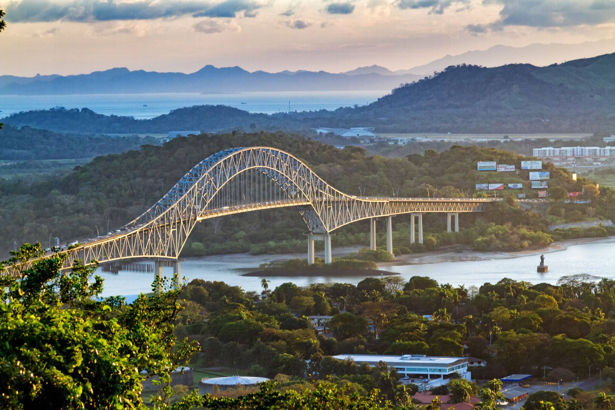 Panoramic aerial view of the Bridge of The Americas over the Panama Canal Pacific Entrance. Sunset scene with a gentle mist in the background. The bridge is spanning two continents - two Americas.