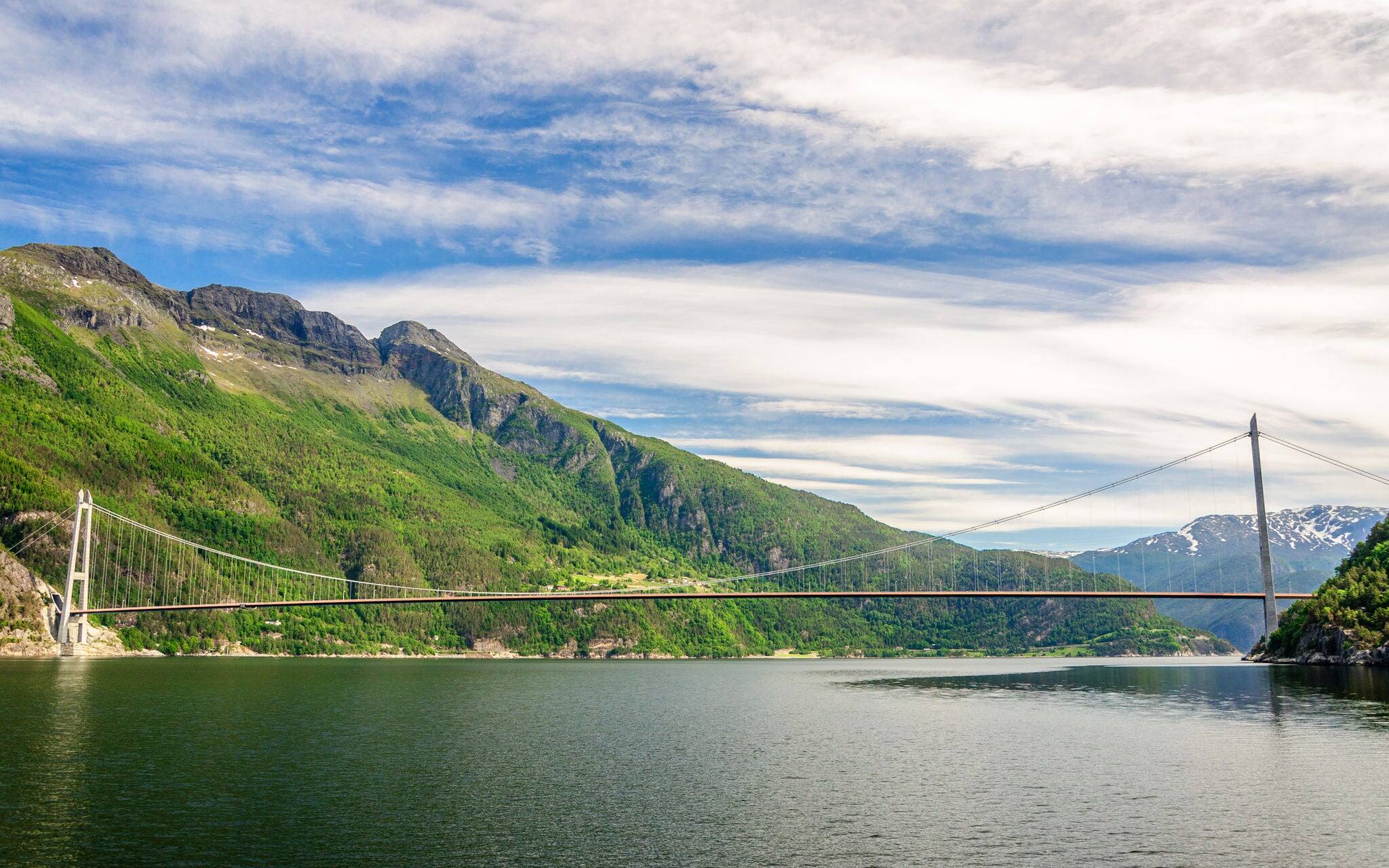 View from a boat sailing to the high-tech the longest suspension bridge in Norway which connects two banks - Oslo and Bergen (Hardanger Bridge), Hardangerfjorden, Norway