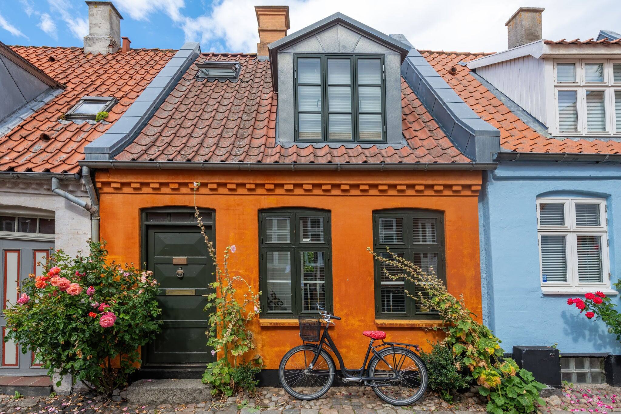 Aarhus, Denmark; August 19, 2020 - A bicycle stands outside a colourful old cottage on a quiet street in Aarhus, Denmark