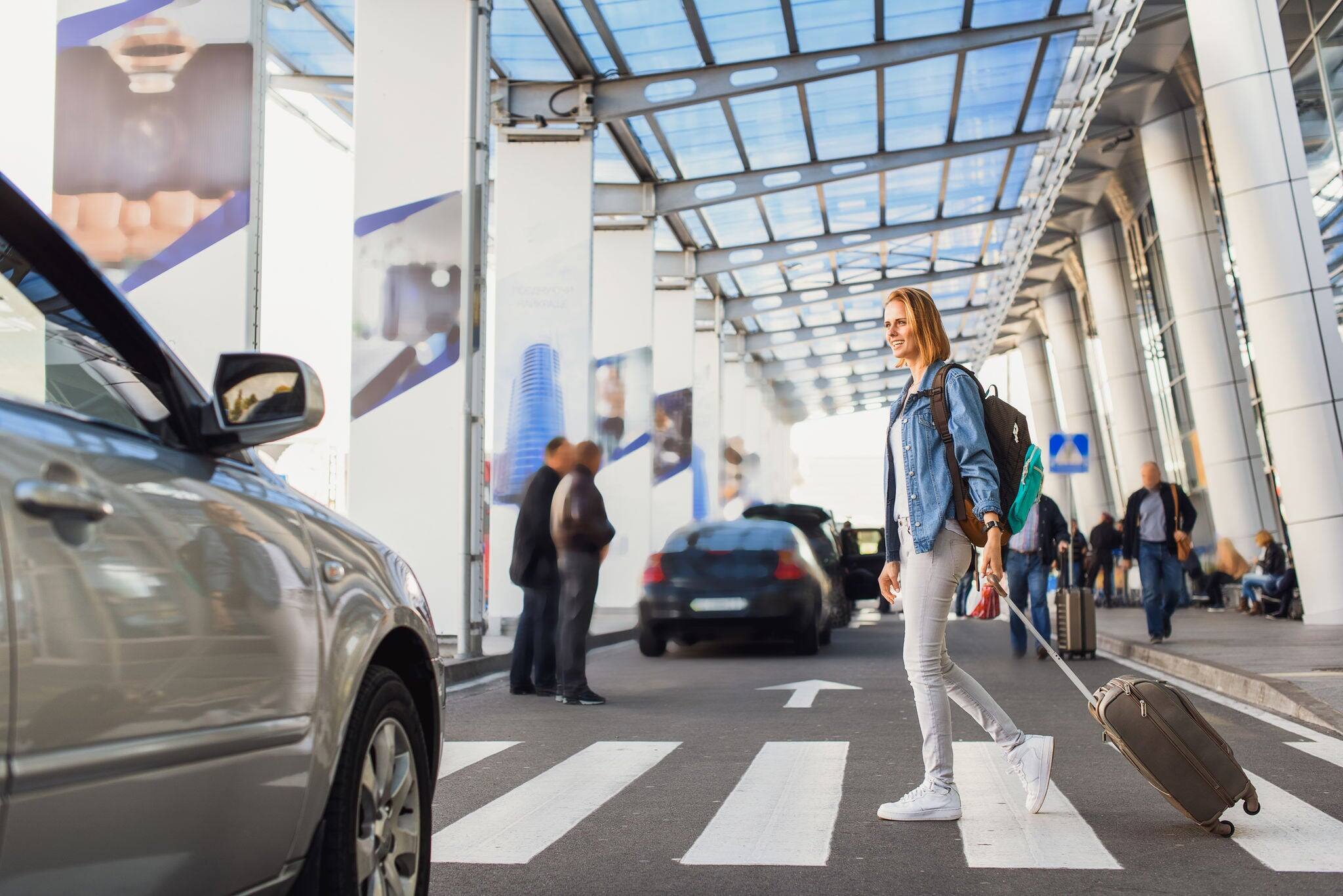 Joyful young woman walking with suitcase