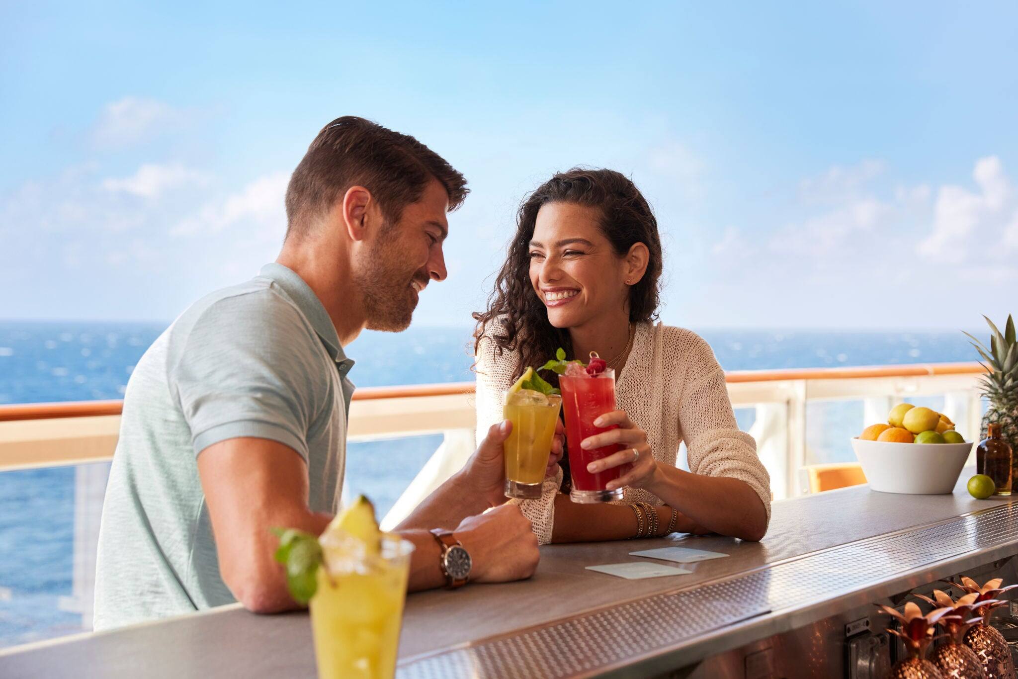 Couple enjoys drinks on a breezy ship deck