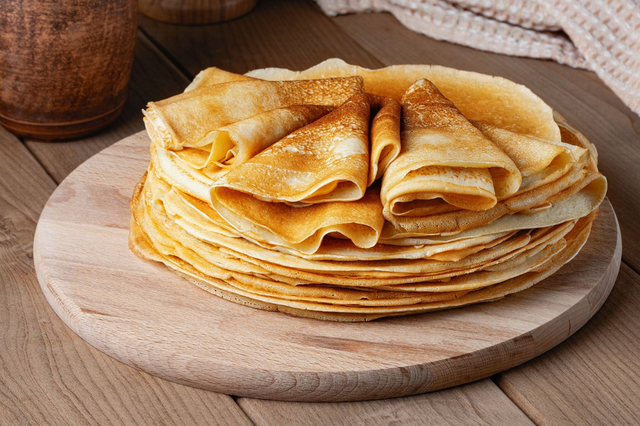 Thin pancakes on a wood plate. Homemade crepes, tasty food. Staple of yeast pancakes, traditional for Russian pancake week (Shrove tide). Thin pancake with crispy crust