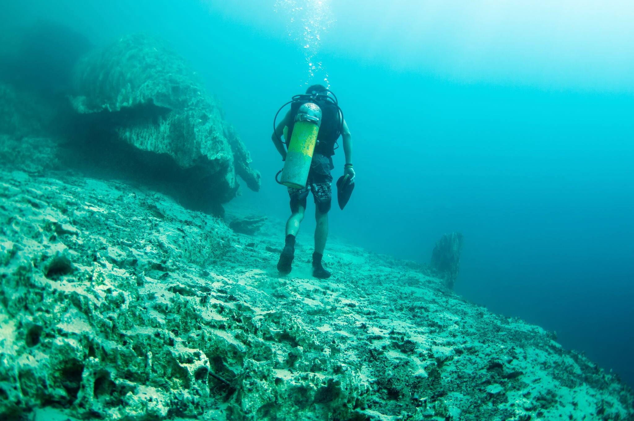 A diver walking underwater, below the hot spring, the different density of hot and cold water makes the vision blurry. Barracuda Lake, Coron, Philippines.