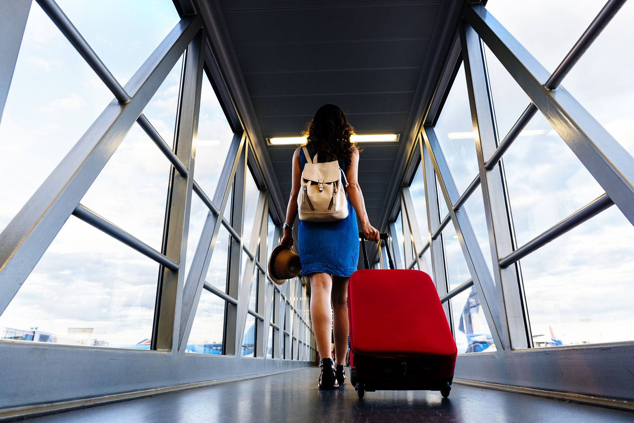 Young girl traveler walking with carrying hold suitcase in the airport. Tourist Concept.
