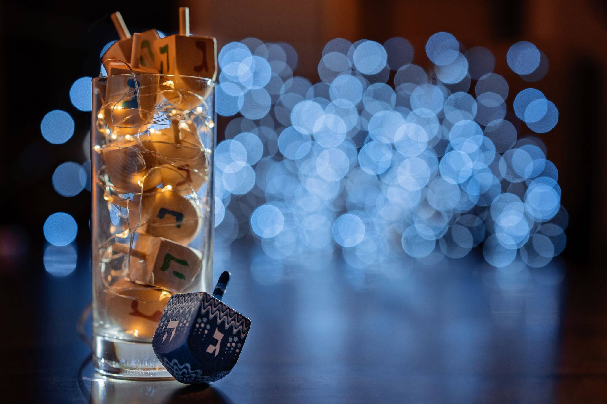 jewish holiday Chanukah/Hanukkah with wooden dreidels / sovivon (spinning top) in the glass over glitter shiny background