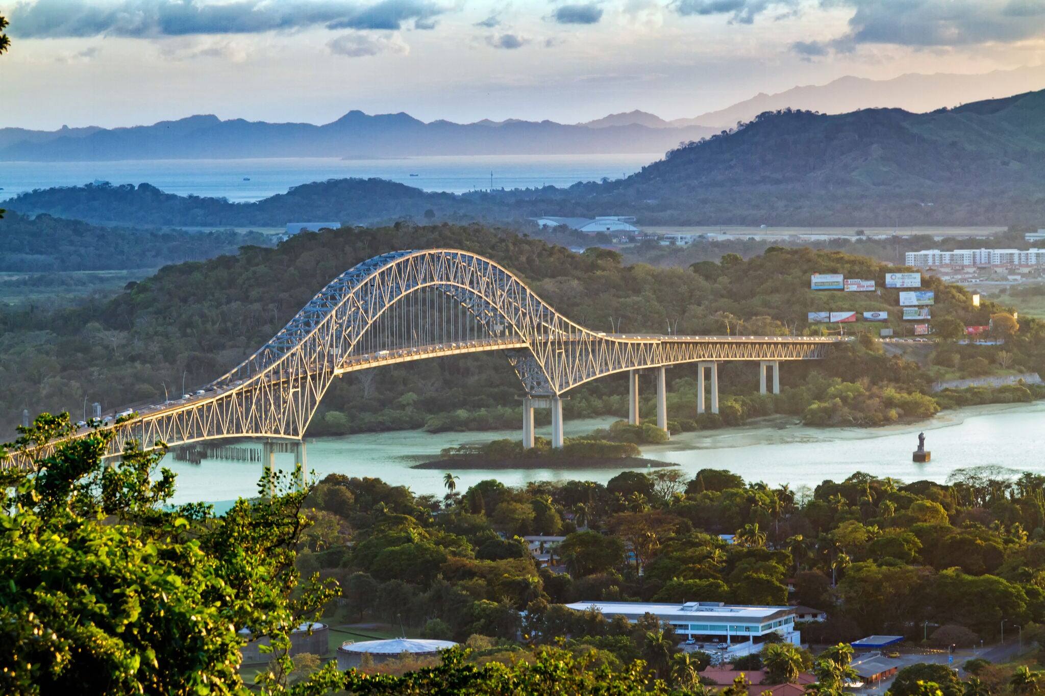 Panoramic aerial view of the Bridge of The Americas over the Panama Canal Pacific Entrance. Sunset scene with a gentle mist in the background. The bridge is spanning two continents - two Americas.