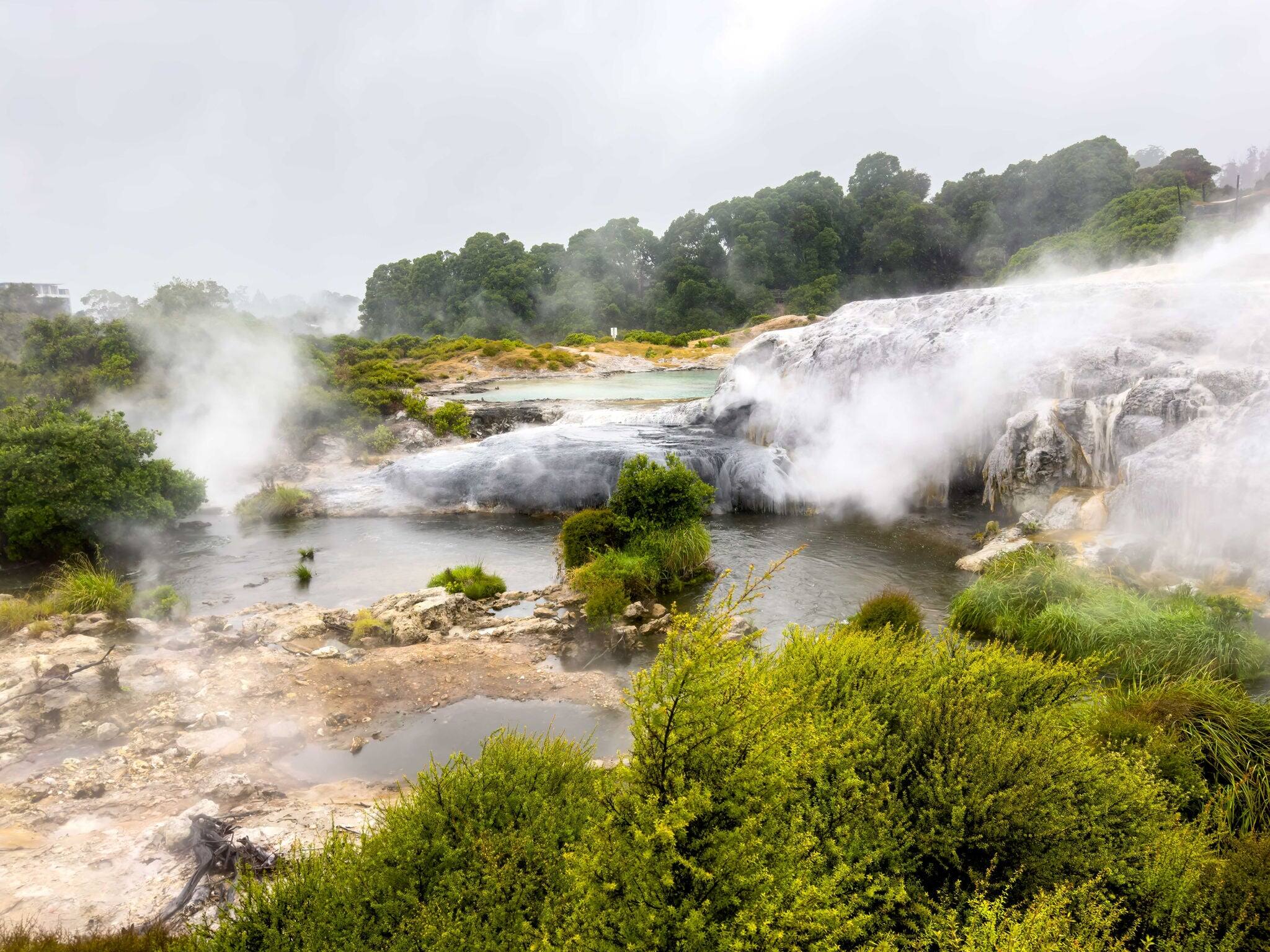 Geothermal geyser steaming over rock formations in landscape of South Island, New Zealand