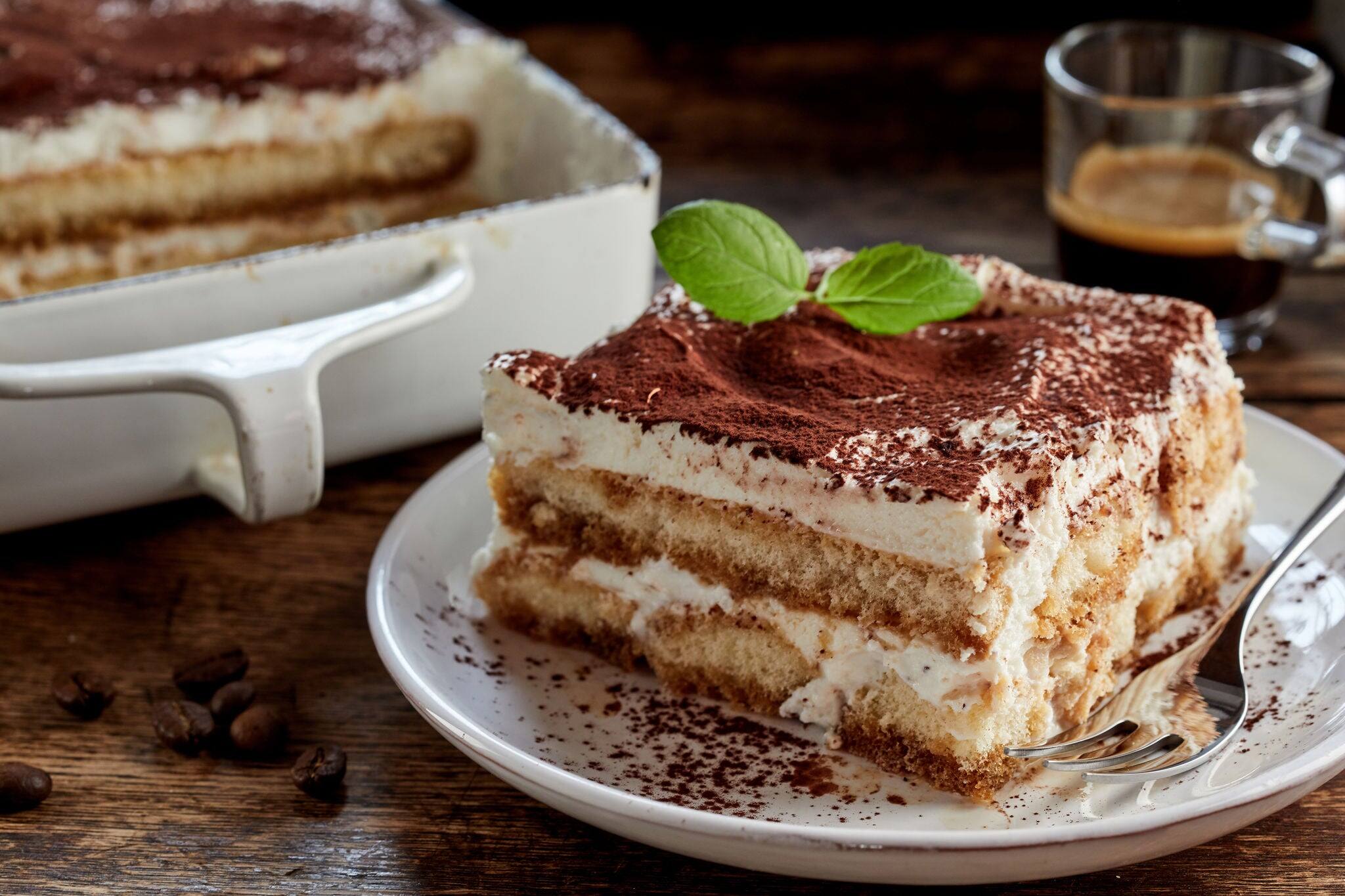 Close up on a portion of gourmet tiramisu Italian dessert topped with a sprig of mint served on a plate at table in a side view