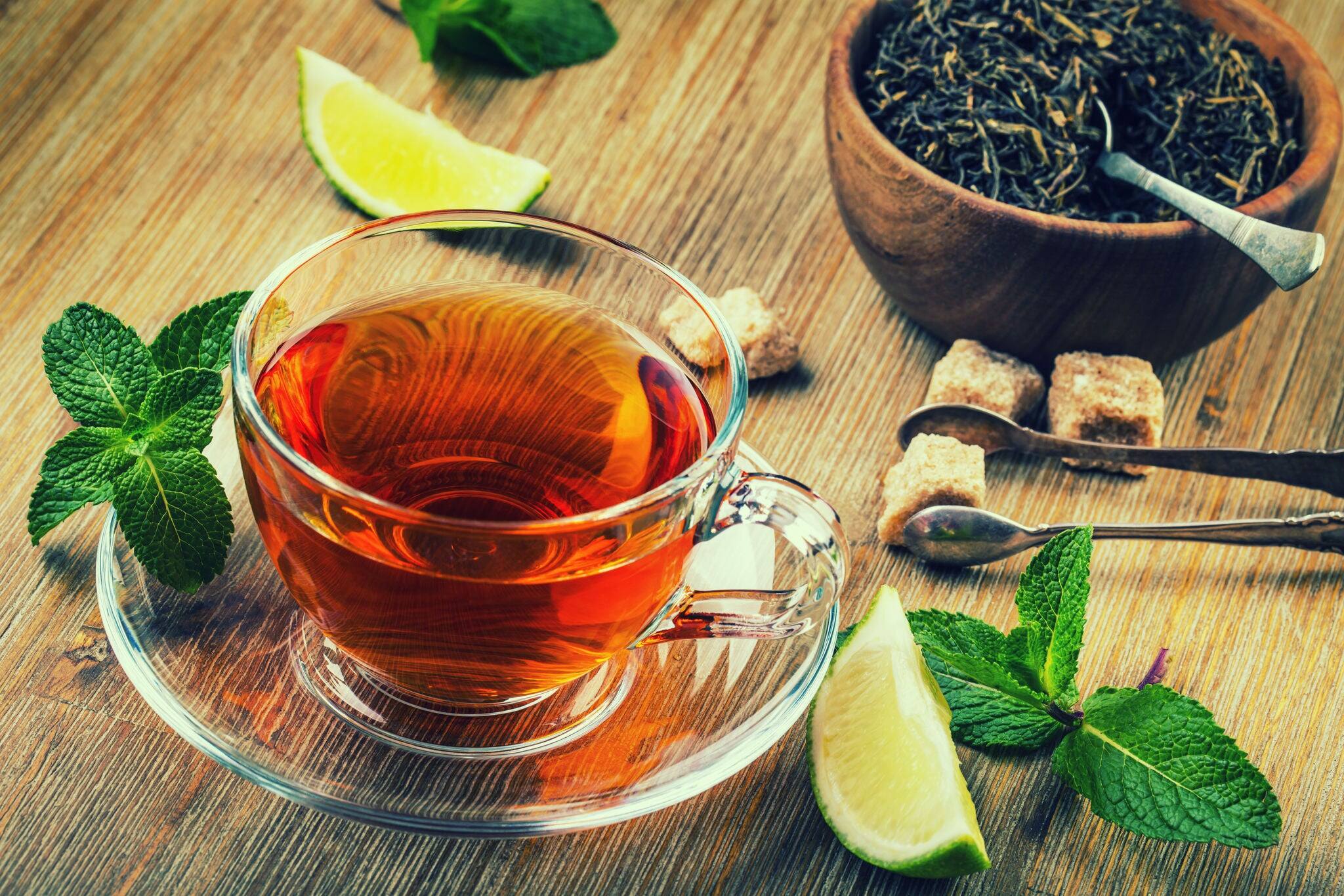 Tea in a glass cup, mint leaves, dried tea, sliced lime, cane brown sugar