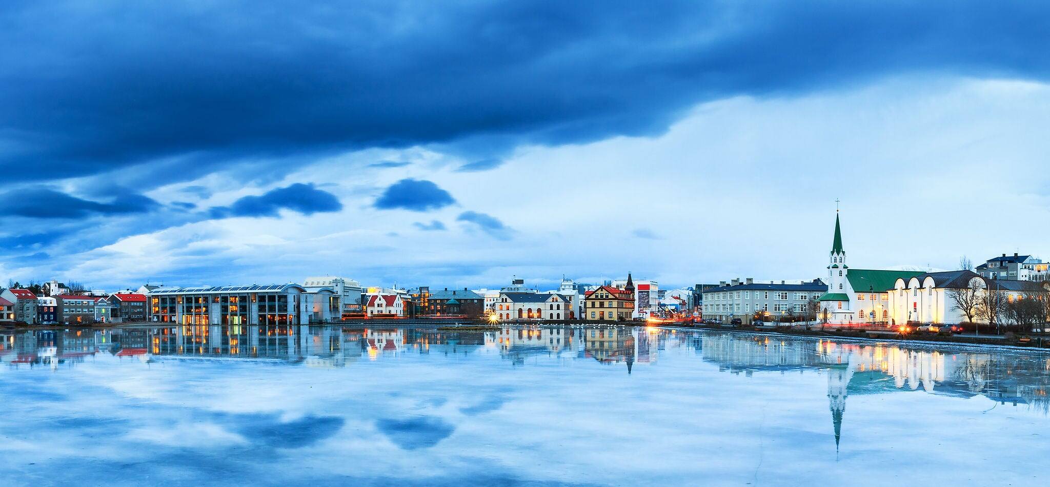 Beautiful panorama of the skyline cityscape of Reykjavik, reflected in lake Tjornin at the blue hour in winter