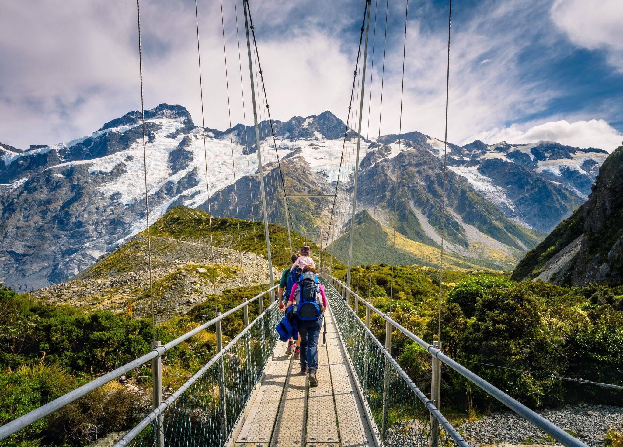 Amazing Nature of Hooker Valley Track in Mount Cook, New Zealand. Young Family walk on Suspension Bridge.