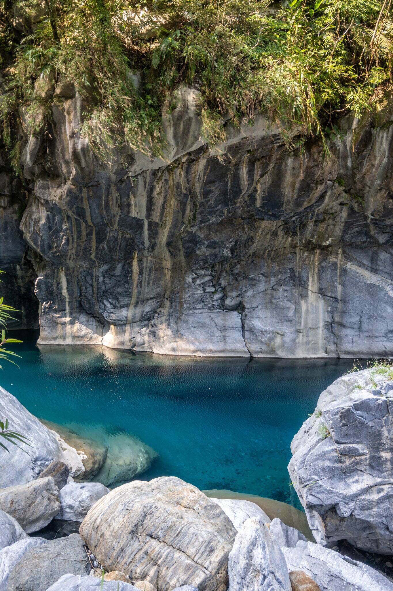 A vibrant blue river flowing through a dramatic mountain canyon, showcasing the stunning natural beauty and dynamic landscape on Shakadang Trail in Taroko National Park, Hualien, Taiwan