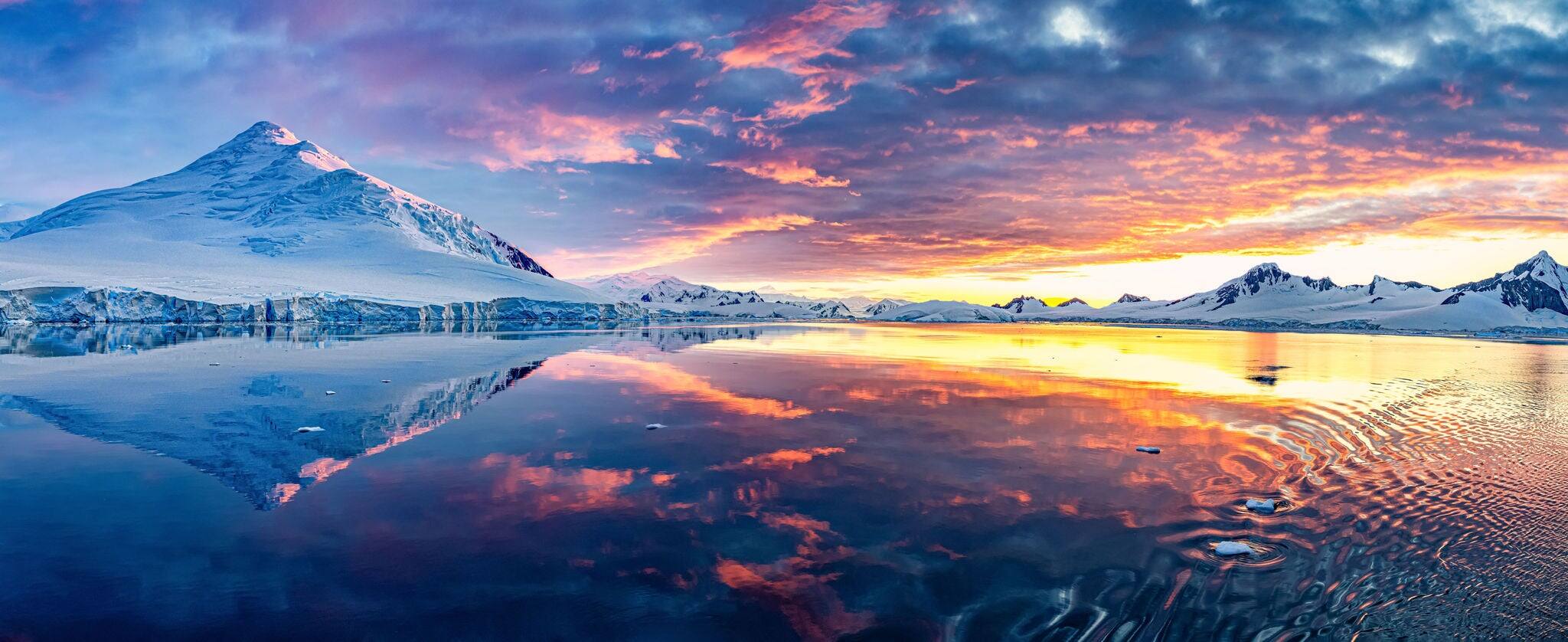 Panorama in very high detail of beautiful Antarctica landscape, mountains next to the sea with breathtaking reflection during midnight sun, sunset and sunrise in once, in Antarctica