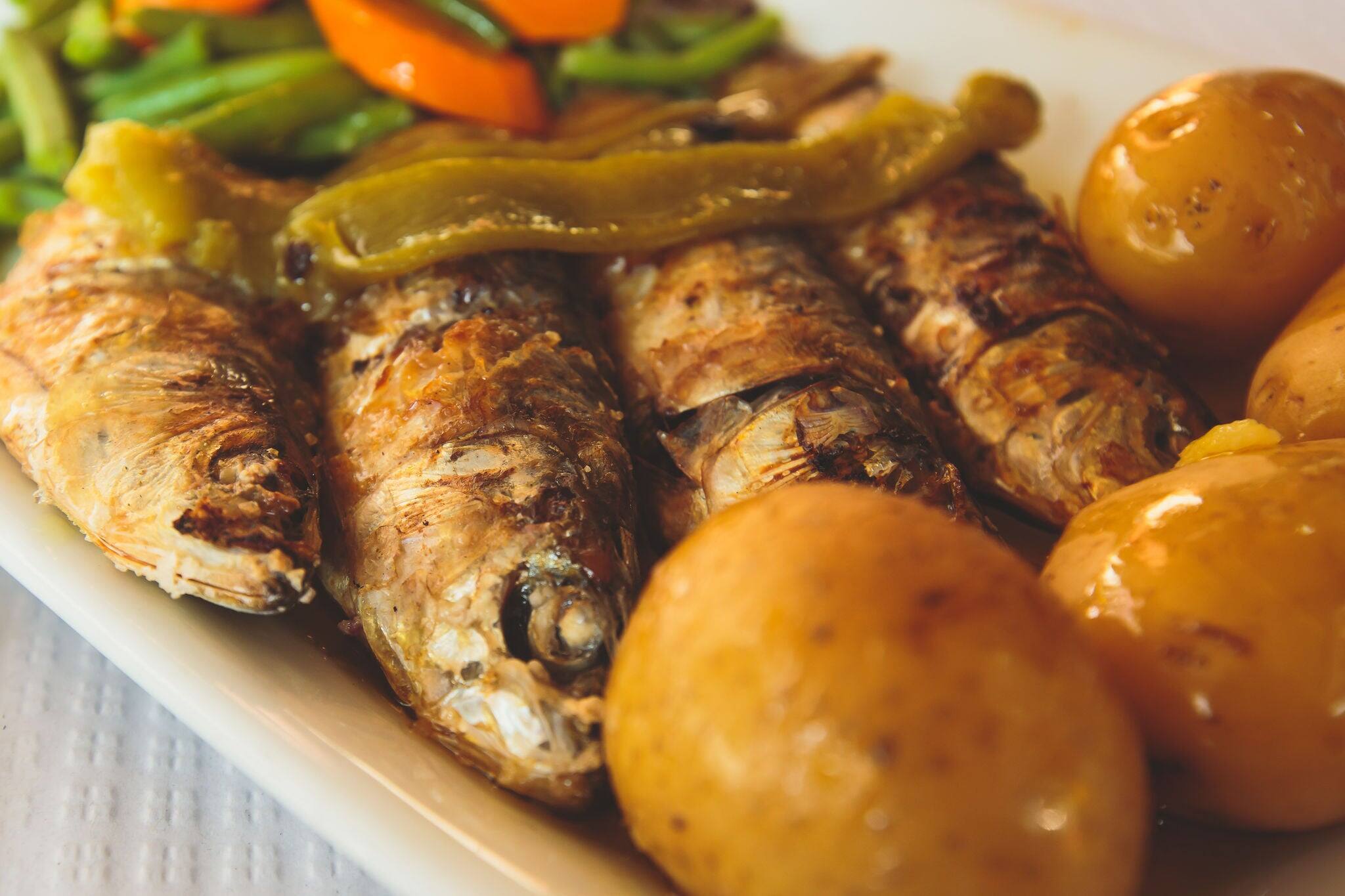 Close-up of portugese traditional grilled sardines sardinas on a plate with potatoes and vegetables, in Lisbon, Potrugal