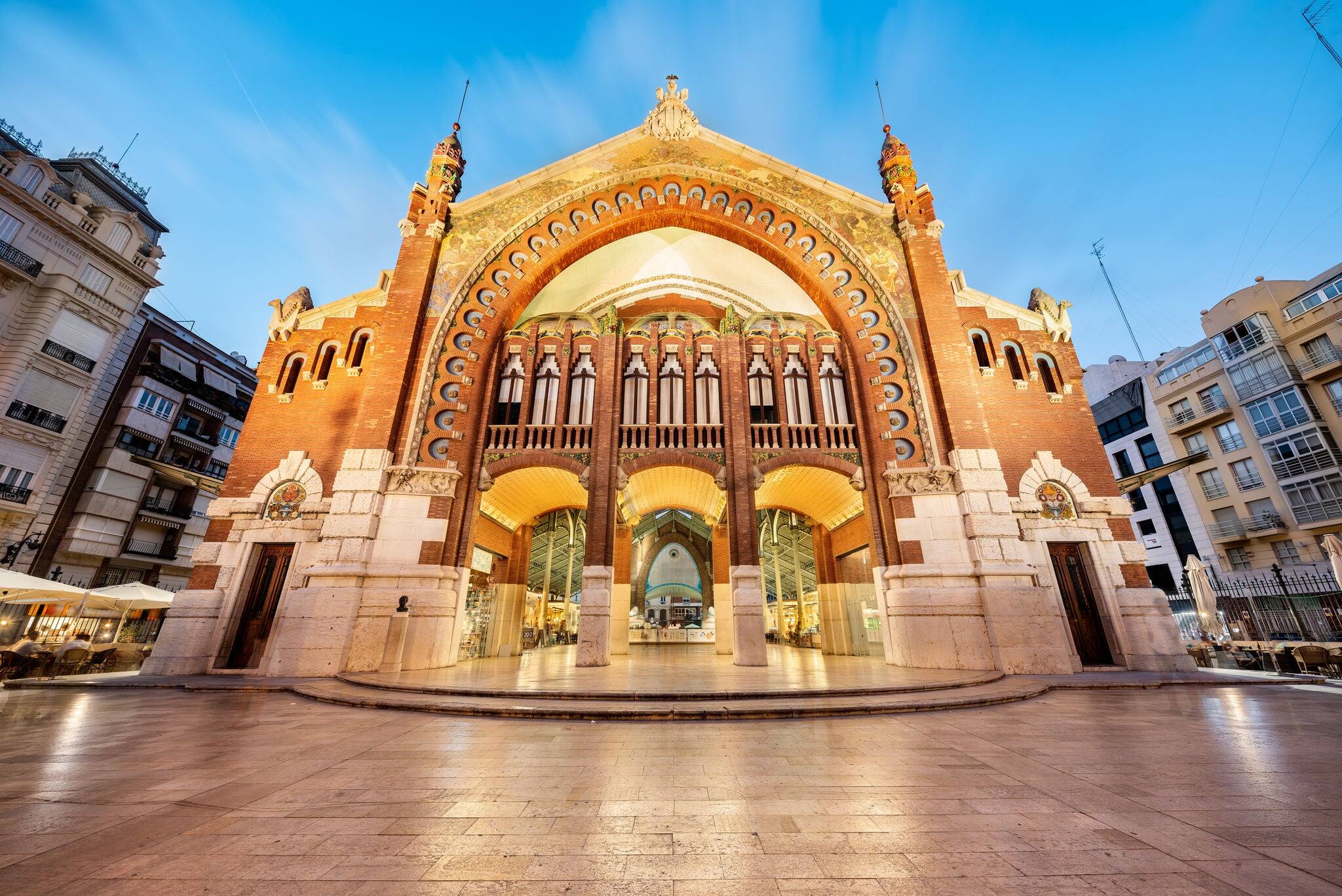 The majestic facade of the Colon Market and his reflection on the floor of the square, taken at the blue hour, Valencia, Spain