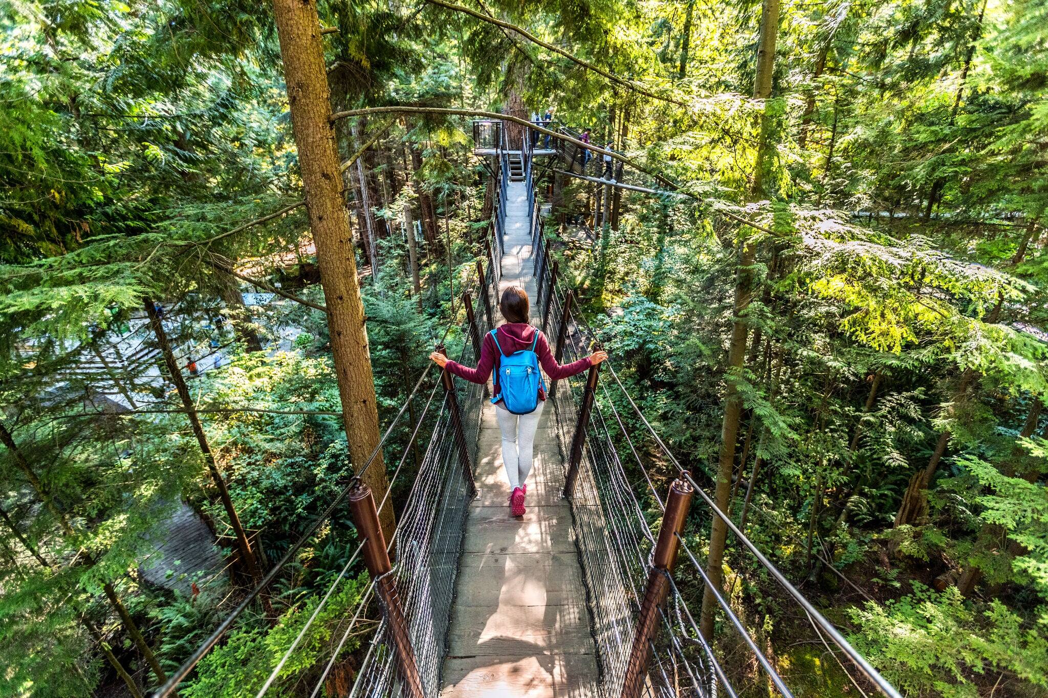 Mujer turística que viaja por Canadá caminando en la famosa atracción Puente de Suspensión de Capilano en el norte de Vancouver, Columbia Británica, destino turístico de vacaciones en Canadá.