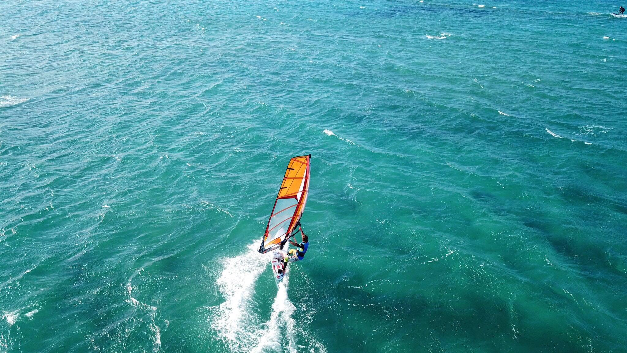 Aerial drone photo of surfer cruising in high speed in popular wavy beach of Chrysi Akti, Paros island, Cyclades, Greece