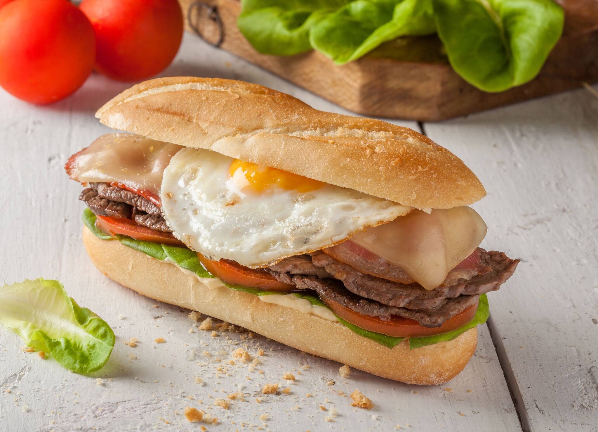 Chivito is a typical sandwich from Uruguay, with lettuce, tomato, bacon, beef, fried or boiled eggs and cheese.