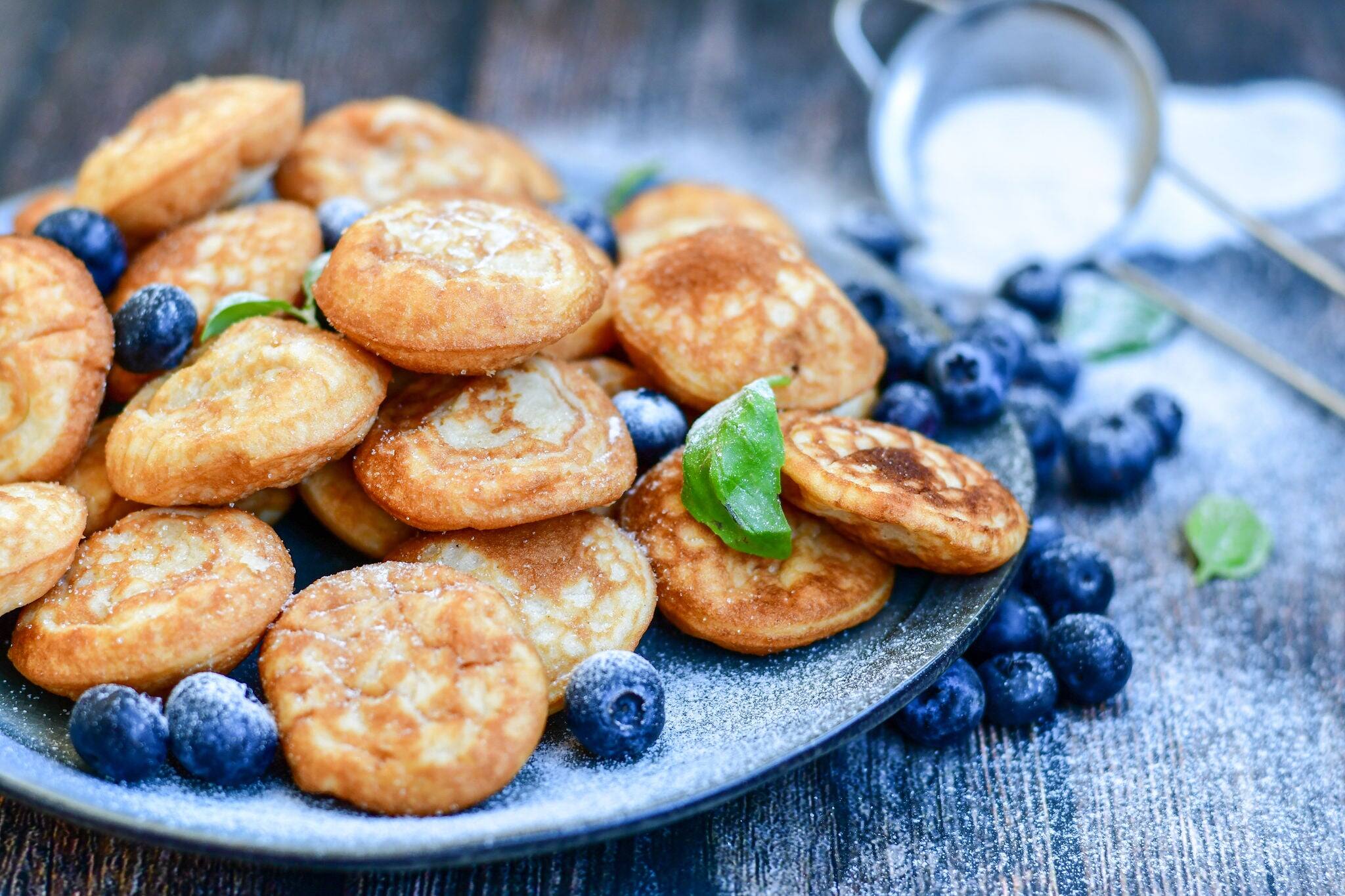 Homemade Dutch Poffertjes  Mini Pancakes with butter , Powdered Sugar  and blueberries
